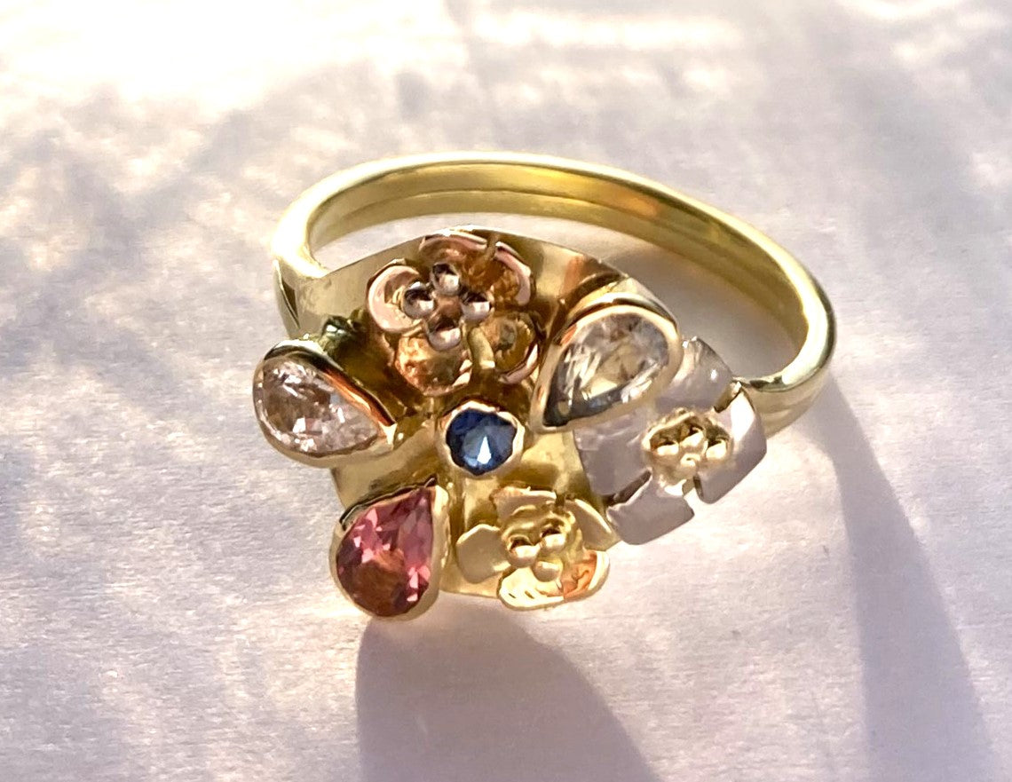 artisan flower and sapphire  yellow gold cocktail ring, on mottled background