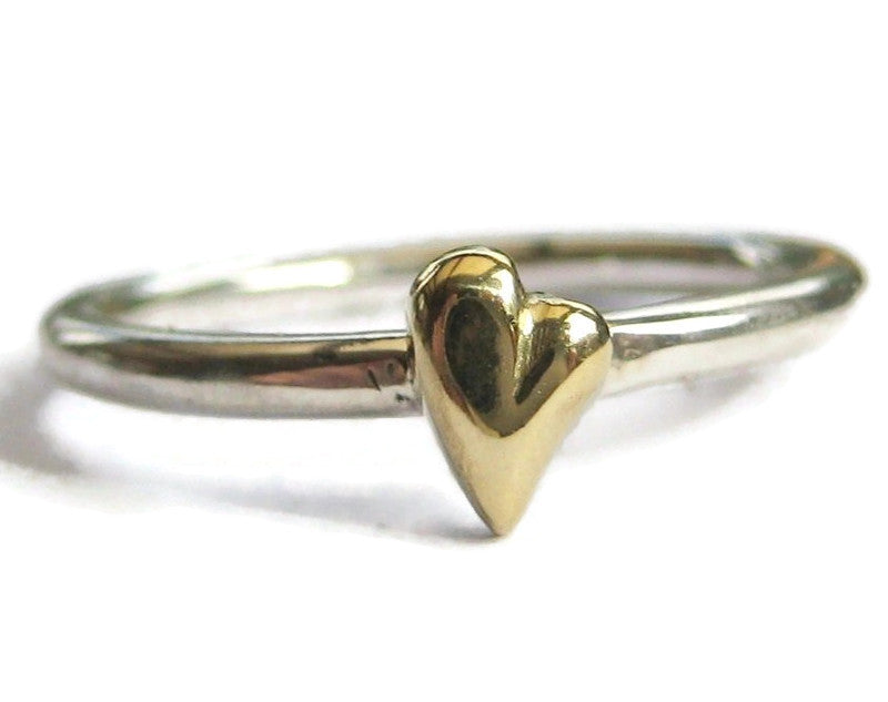 silver ring with carved yellow gold heart, on white background