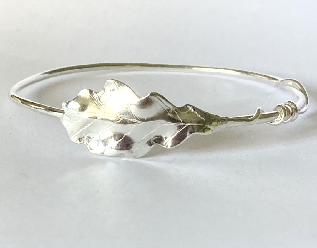 silver oak leaf bangle with pretty curling stem on grey background