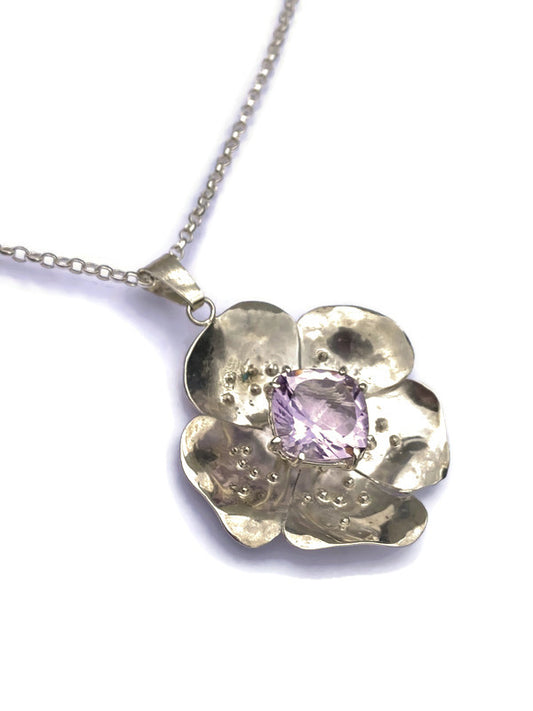 large silver rose pendant with purple amethyst gemstone in the center on white background