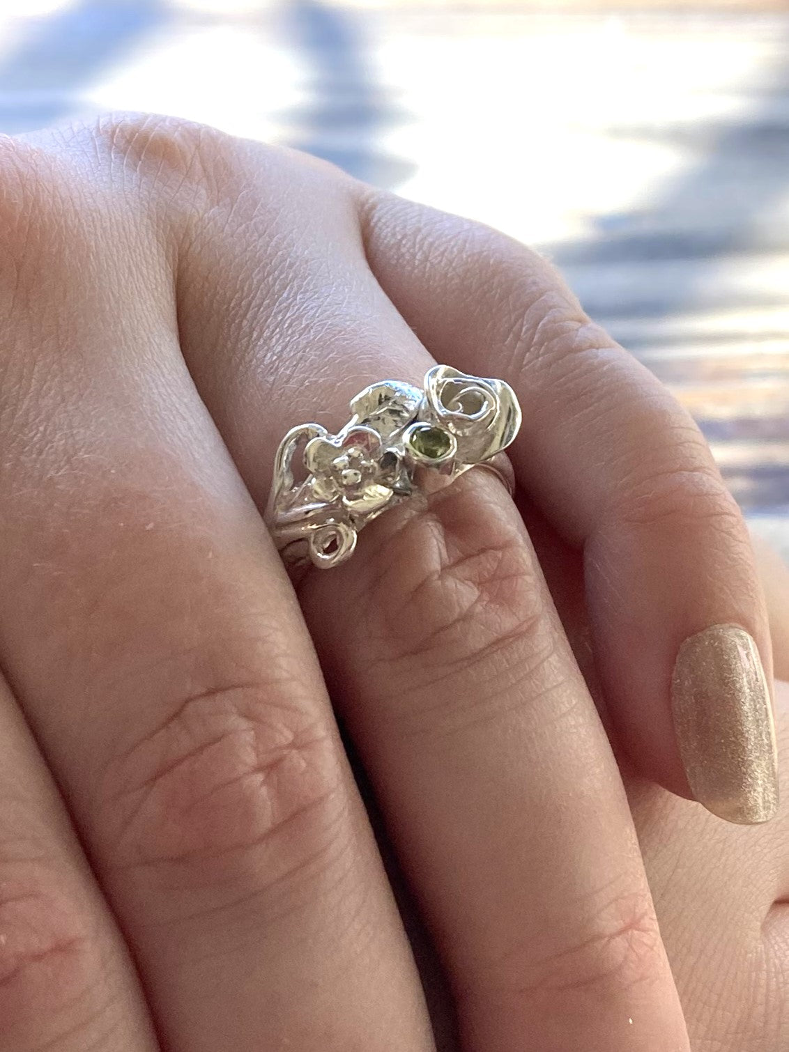 silver floral cluster ring with green peridot, on ladies hands