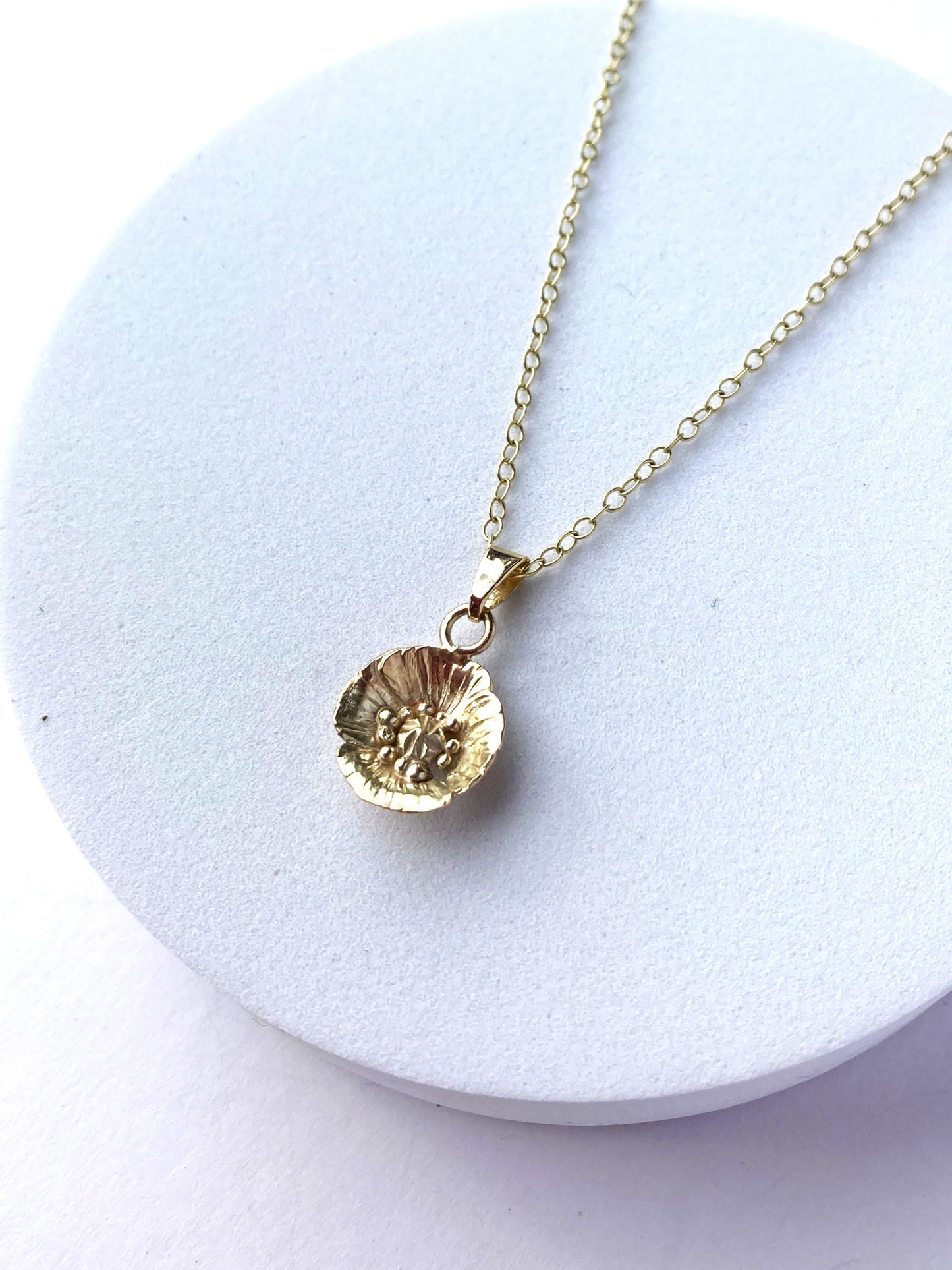 hand forged gold poppy pendant and chain on white background