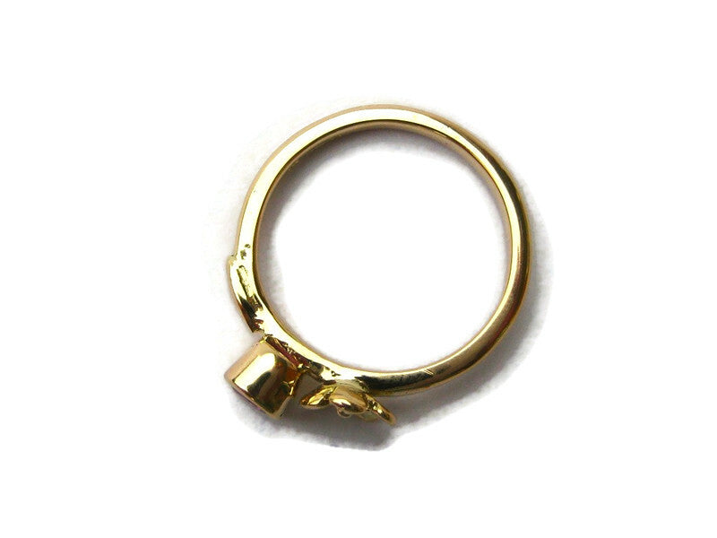 side view of gold solitaire ring, on white background