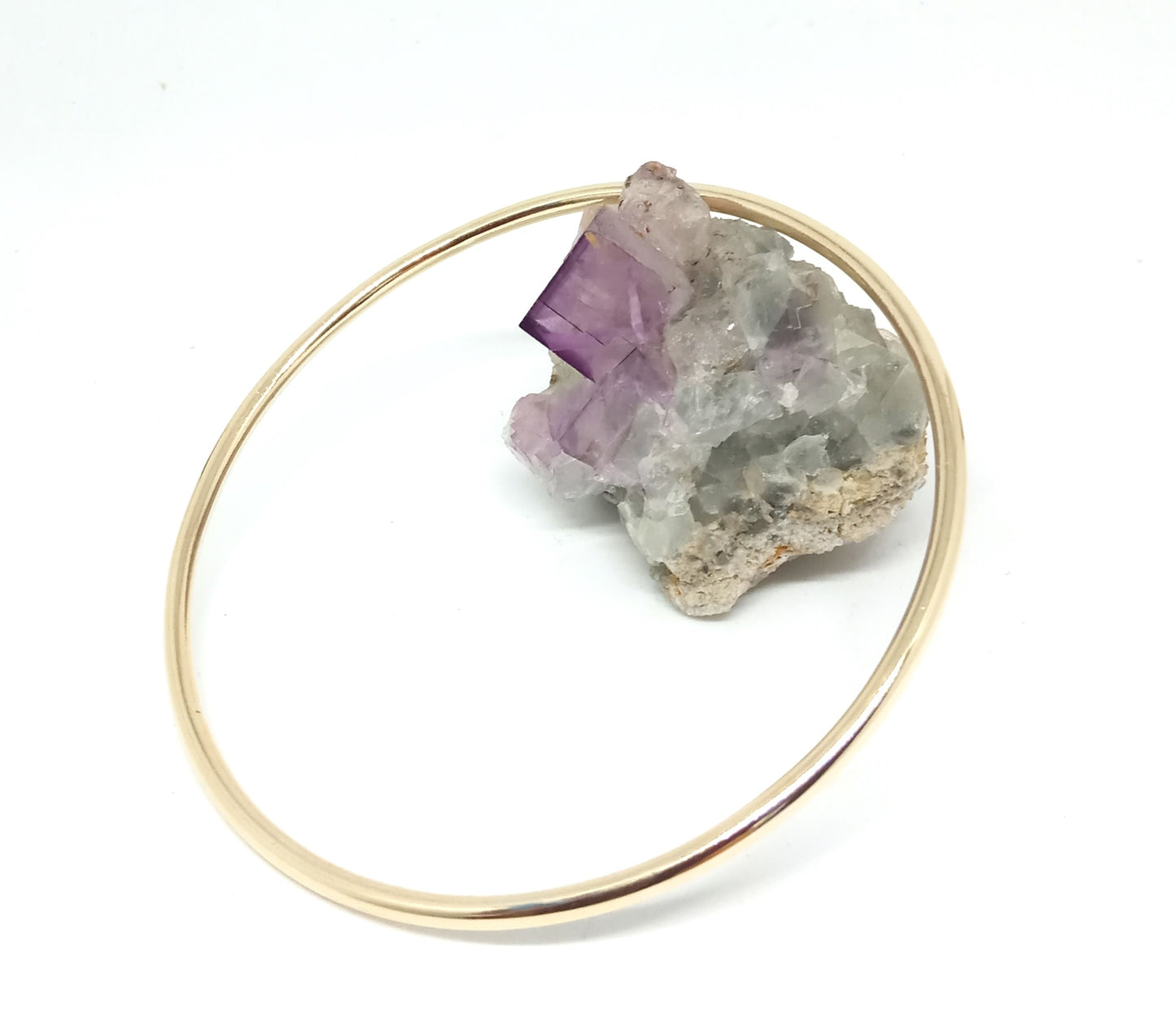 9ct yellow gold circle bangle bracelet LGBTQ unisex jewellery, leaning on raw amethyst crystal, on white background