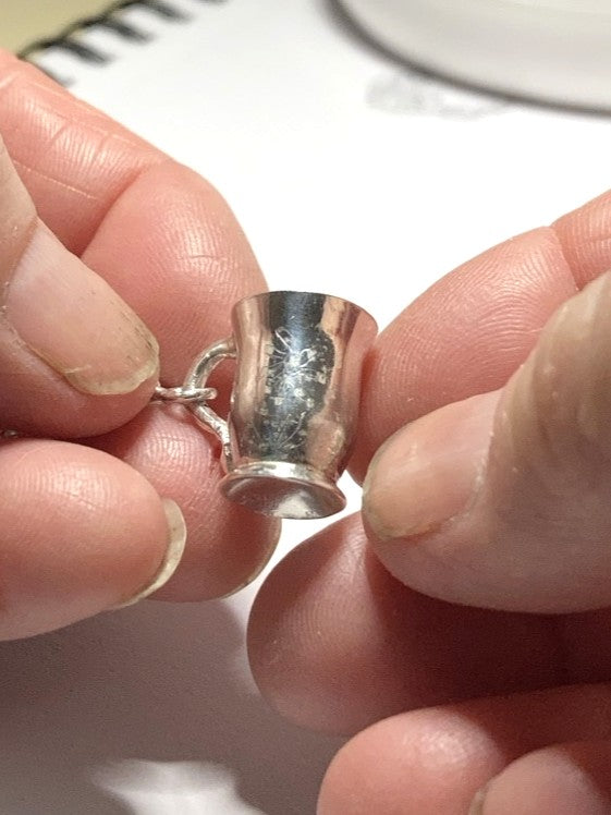 tiny silver mug pendant in hands