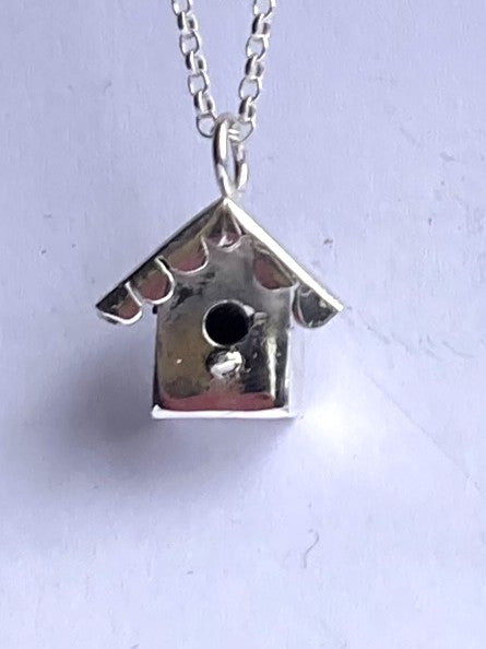 small birdhouse nest box pendant handmade in sterling silver on grey background