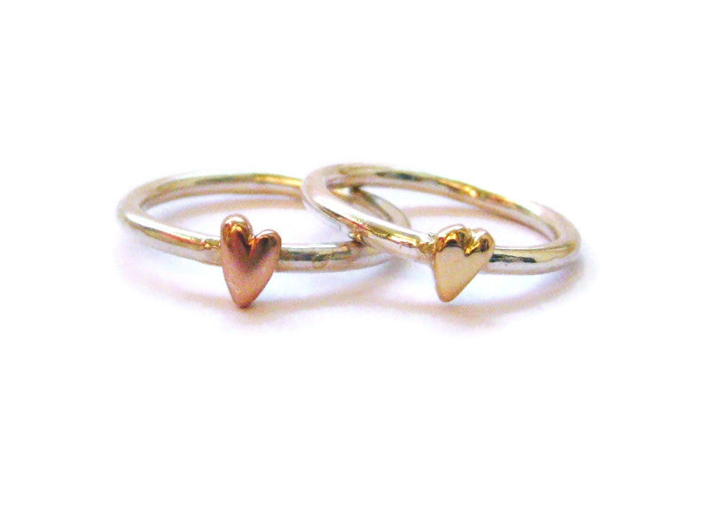 two silver rings with rose gold and yellow gold hand carved hearts, on white background