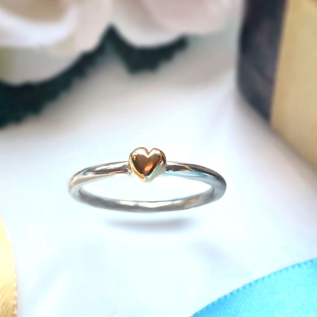 silver halo ring with solid gold heart, on white background