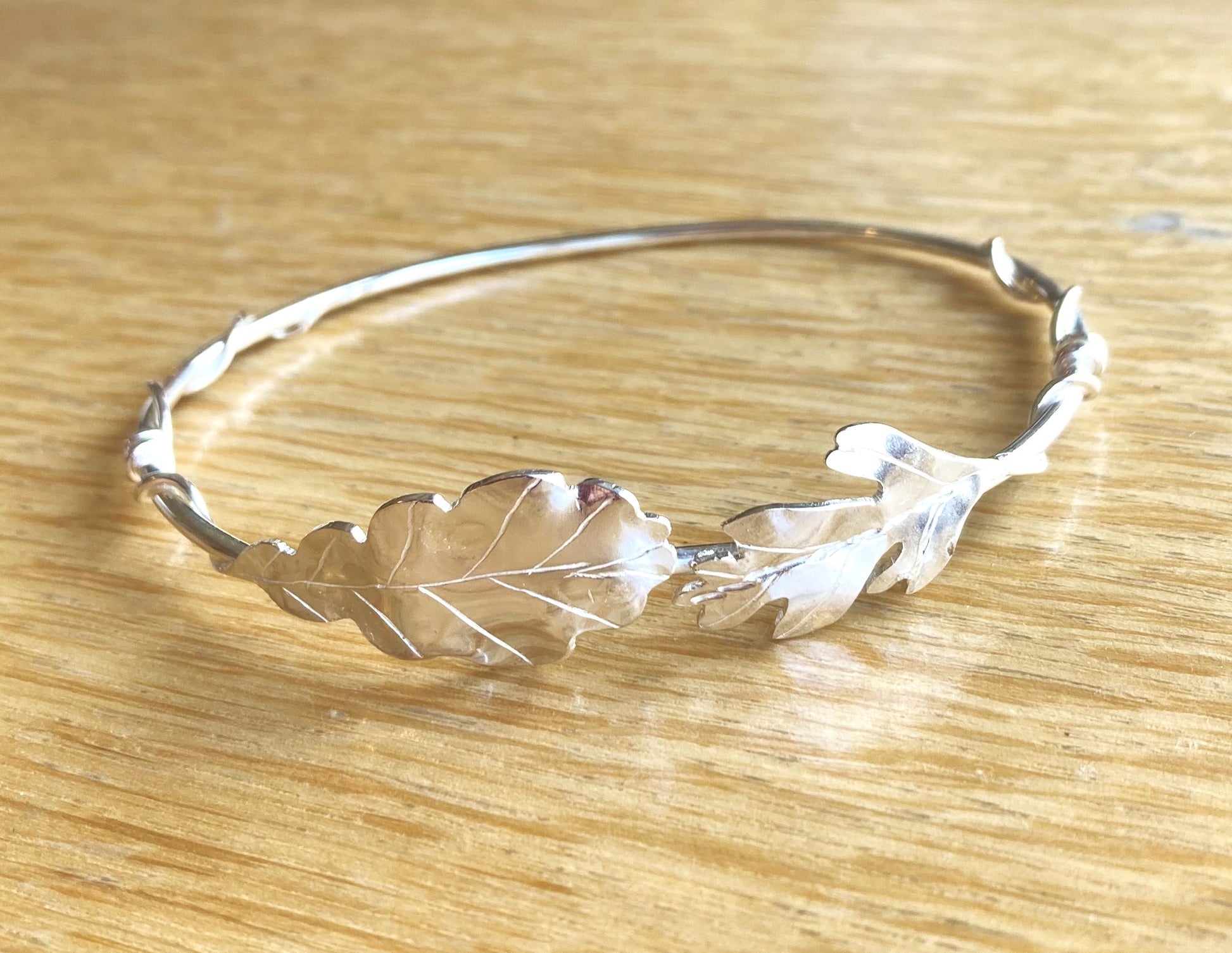 silver bangle with oak and hawthorn leaves, on wood background