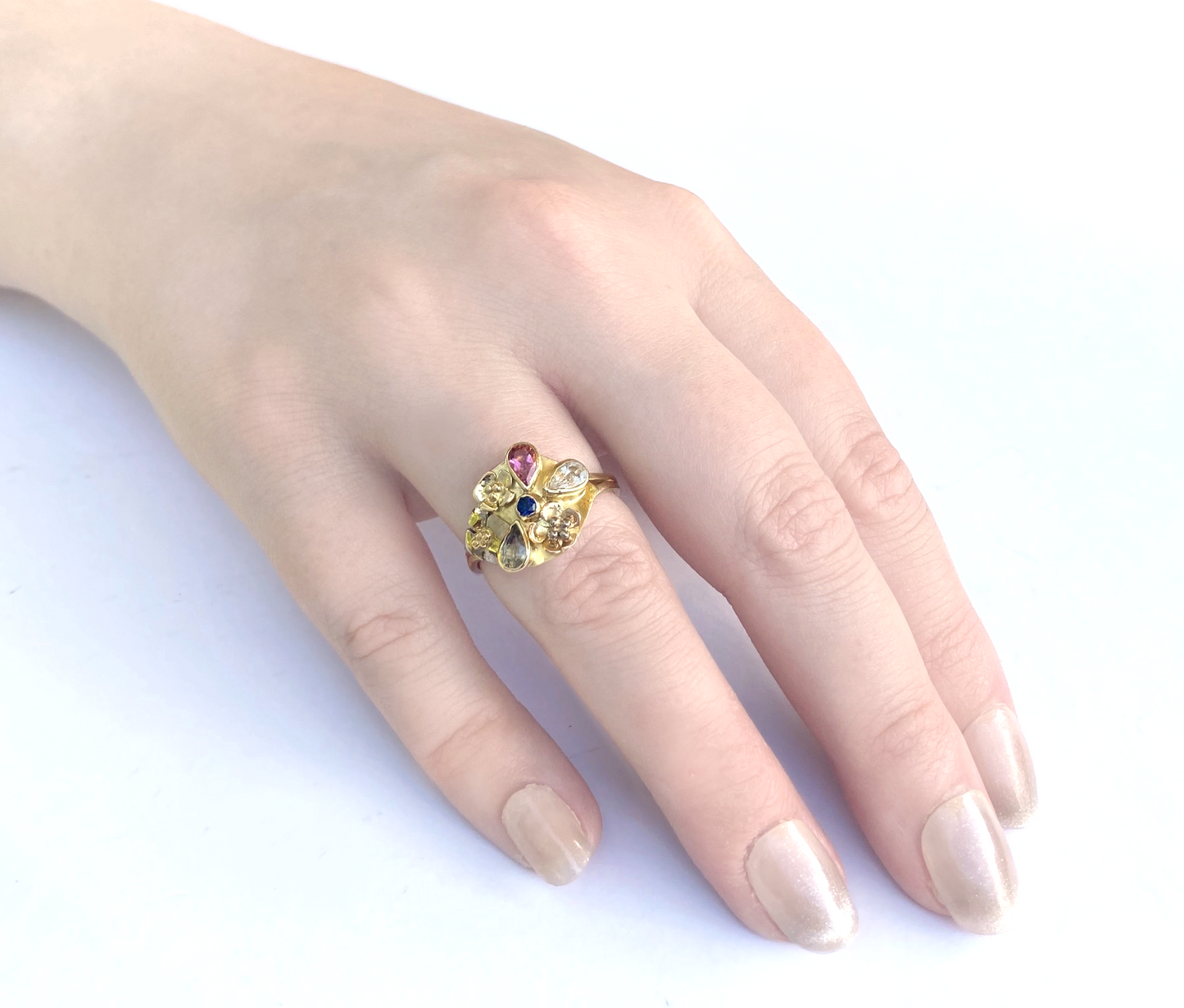 18ct yellow gold sapphire cluster ring on ladies hand, on white background