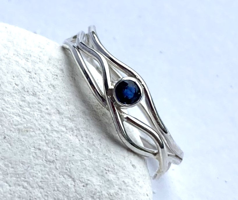 sapphire set silver wire ring, leaning on white pebble