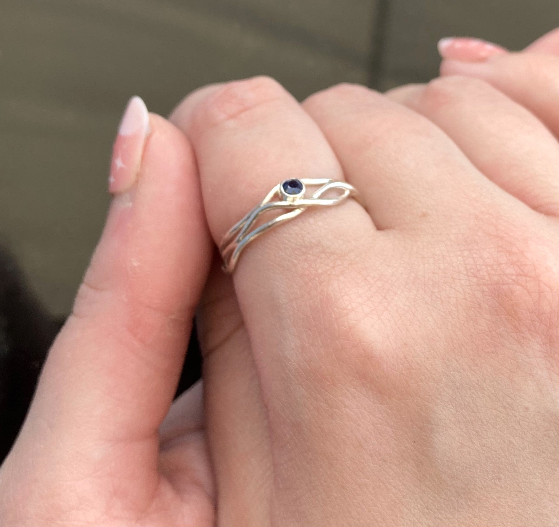 delicate wire ring set with blue sapphire, worn on hand