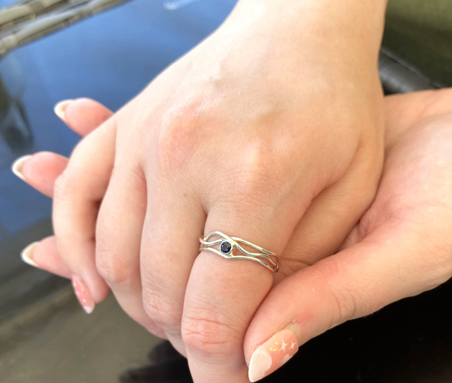 clasped hands wearing silver and sapphire ring