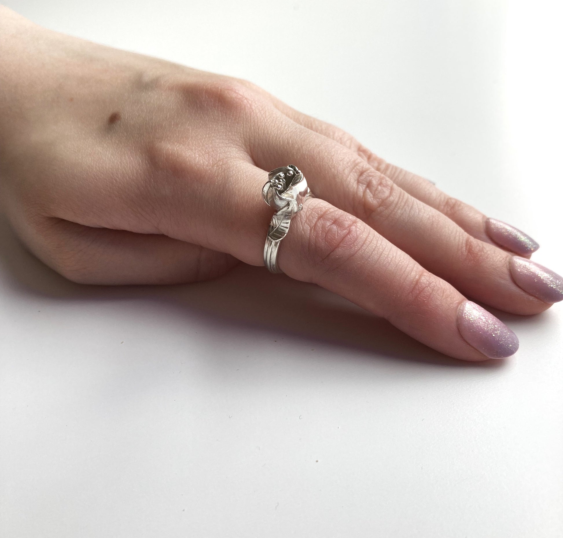 hand wearing silver flower and leaf ring