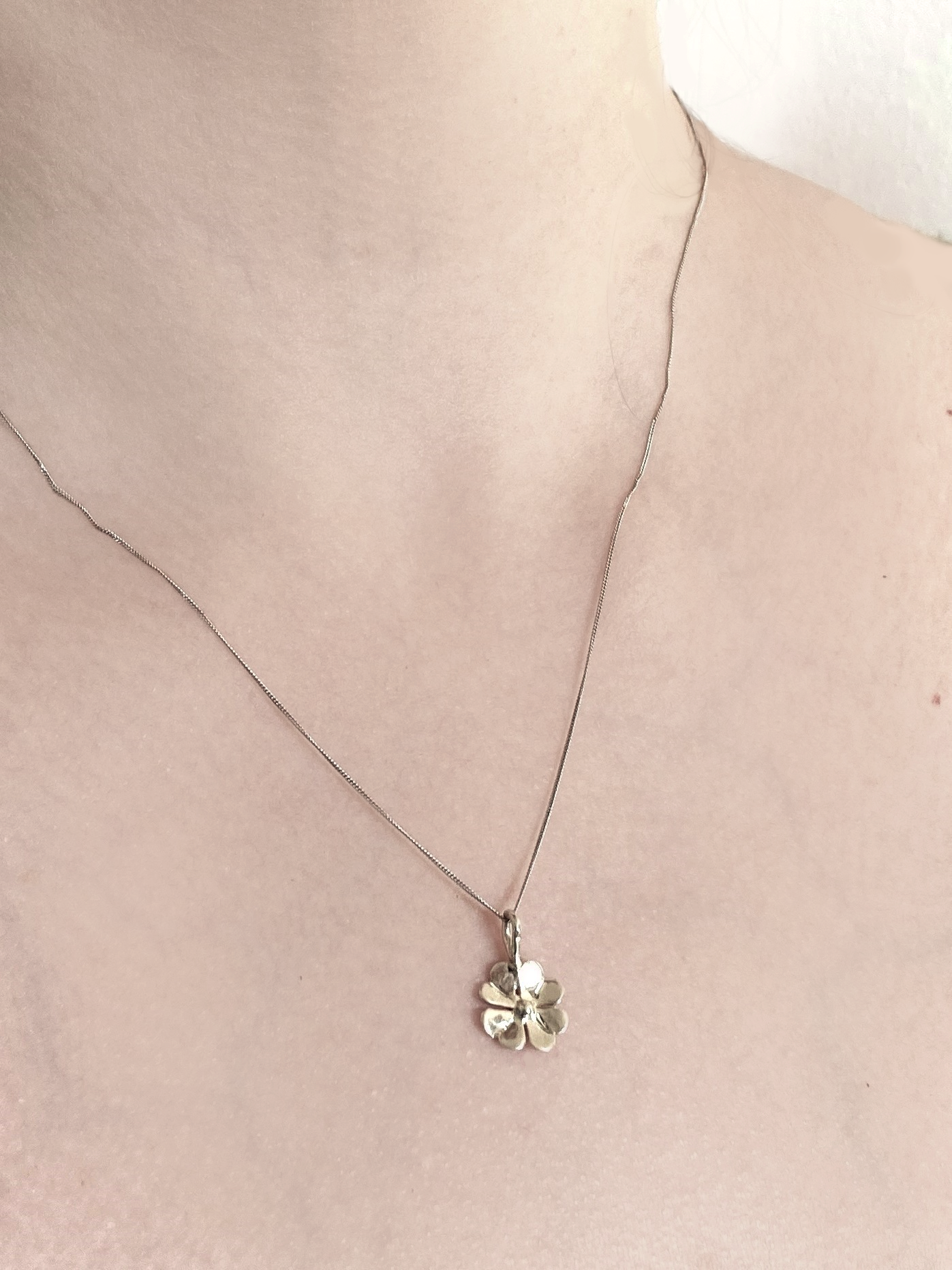 small four leaf clover pendant in white gold, on woman's neck